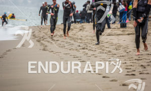 Athletes exit water and run up beach at the 2014 Escape from Alcatraz Triathlon on June 1, 2014 in San Francisco, CA